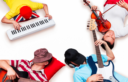 asian pop band lying & playing songs on white floor for music backgroundの写真素材
