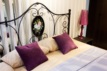 classic iron headboard in master bedroom with purple cushion & lampの写真素材
