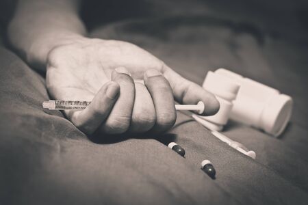 overdose asian male drug addict on bed, narcotic syringe in his handの写真素材