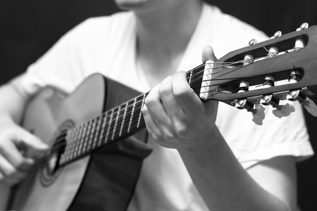 asian male musician playing acoustic guitar, black and whiteの写真素材