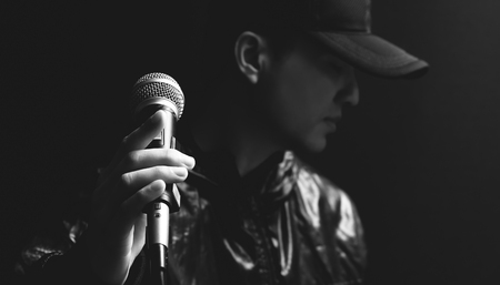 asian male singer hands on microphone, black and white