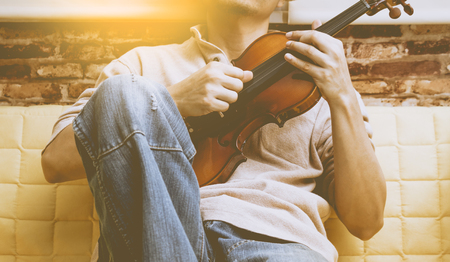 asian man enjoy playing violin on yellow seat for relaxationの写真素材