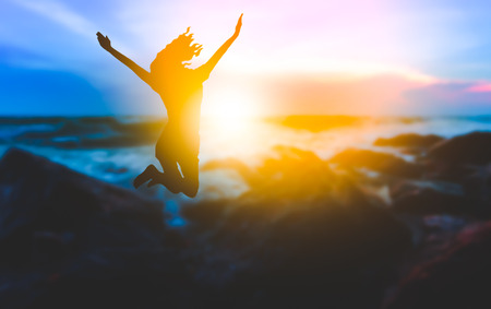 teen girl jumping on the beach in the eveningの写真素材