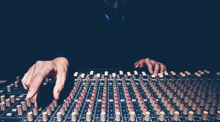 Male sound engineer hands working on audio mixing console in recording studio