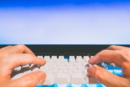 fingers on computer keyboard with copy space on blue screen monitor