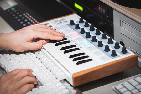 professional musician hands working on midi keyboard and computer in recording studio