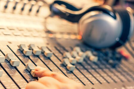 male sound engineer, dj hand working on audio mixing console in recording, editing, broadcasting studioの写真素材