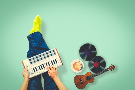 top view of male musician playing keyboard with ukulele, record, cup of coffee on green floorの写真素材