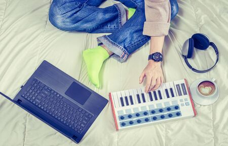 Male composer, song writer enjoy playing piano and recording a song on midi keyboard and laptop...