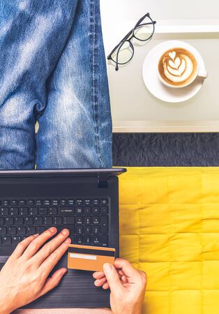 top view of man holding credit card for online shopping in living room. e-commerce conceptの写真素材
