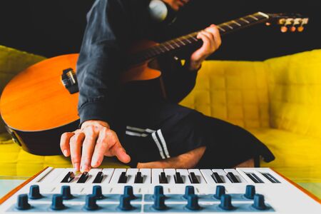 male songwriter playing guitar and keyboard for creating melody, harmony in a song. song writing conceptの写真素材