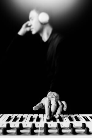 male asian musician, artist, songwriter playing keyboard synthesizer and listening music for creating new sound in his songの写真素材
