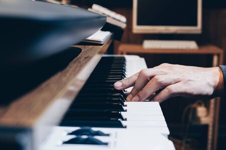 male musician, arranger, producer hand playing on piano keys in home studioの写真素材