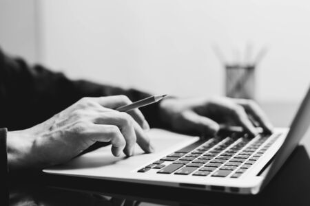 male student working on laptop computer with pencils. black and white