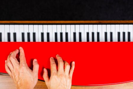 male musician hands enjoy practicing piano lesson on red piano lid, music backgroundの写真素材