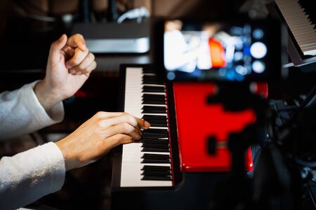 music vlogger streaming a live video while playing piano in home studio