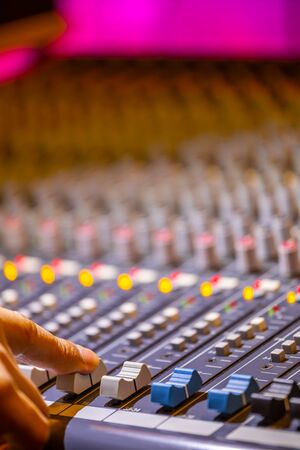 sound engineer fingers adjusting on audio mixing console fader. recording, broadcasting conceptの写真素材