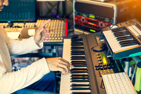 male musician, producer, composer playing electric piano in home studio