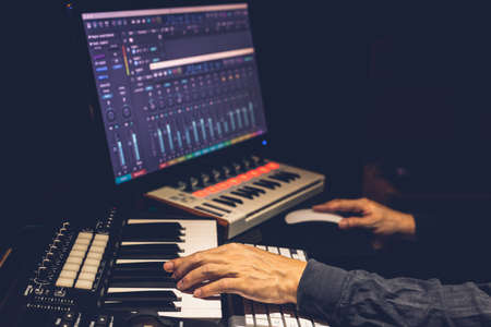 music producer hands arranging a song on midi keyboard and computer in studio. music production...