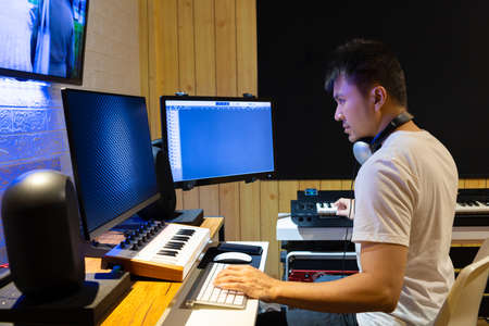 asian professional producer composing, editing music score on movie footage. recording, post production conceptの写真素材