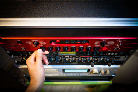 sound engineer hand tuning knobs of studio gears, pre-amp, audio interface, effect signal processor for TV radio broadcasting, post production or music conceptの写真素材