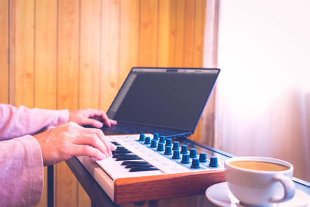 male music composer hands arranging a hit song on laptop computer in living room