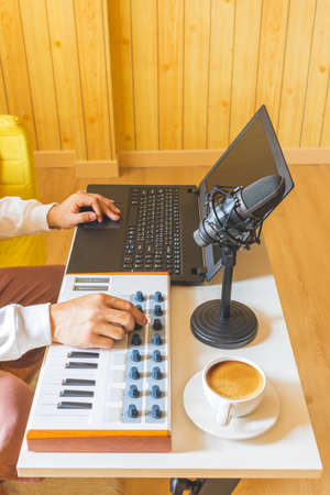 amateur music composer arranging a song and learning online piano lesson from internet on midi keyboard and laptop computer in living roomの写真素材