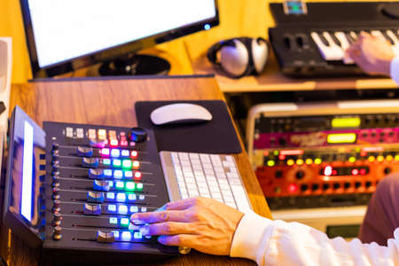 male composer hands working on professional audio equipment in home recording studio. music...
