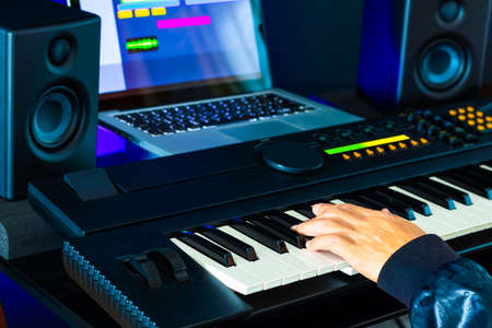 professional musician, producer hand playing on midi keyboard for recording music instrument track...
