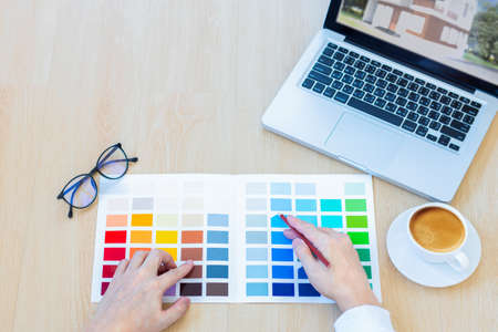 male designer using graphics tablet to choosing color swatch samples chart for selection coloring with laptop computer at workplaceの写真素材
