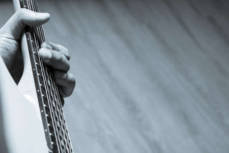 close up male musician left hand playing chord on electric guitar neck. music background
