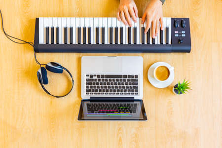 top view of male composer hands playing midi keyboard for recording on laptop computer. music production, home studio or online music e-learning conceptの写真素材