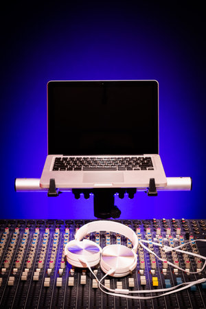 white headphone on audio mixing console and laptop computer background. music concept