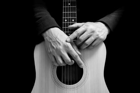 black and white male guitarist hands on acoustic guitar body, isolated on black. music backgroundの写真素材