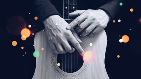 black and white male guitarist hands on acoustic guitar body with colorful bokeh, isolated on black....