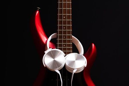 white headphone on red electric bass guitar on black. music backgroundの写真素材