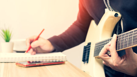 male songwriter writing a hit song while playing white electric guitar. song writing conceptの写真素材