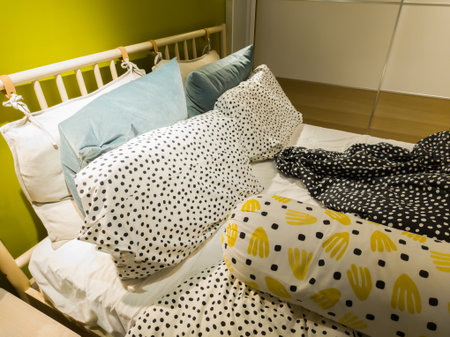 Cozy bedroom interior with colorful pillows and patterned bedding on an unmade bed. Modern home...