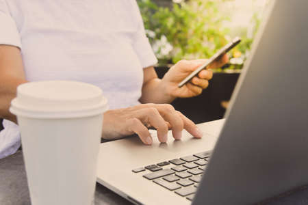 Woman working with laptop and smartphone sitting outdoor in a beautiful terrace. Female using...