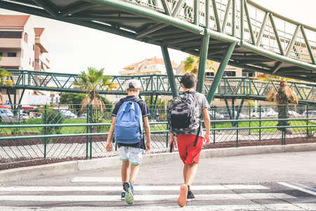 Sad young boys walking in the city, going to the college for the first day of school. Teenagers with backpack walks in urban contest. Back to secondary school. Education, lifestyle, youth, concept.の写真素材
