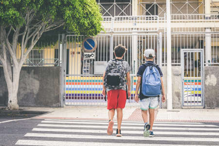 Sad young boys walking in the city, going to the college for the first day of school. Teenagers with backpack walks in urban contest. Back to secondary school. Education, lifestyle, youth, concept.の写真素材