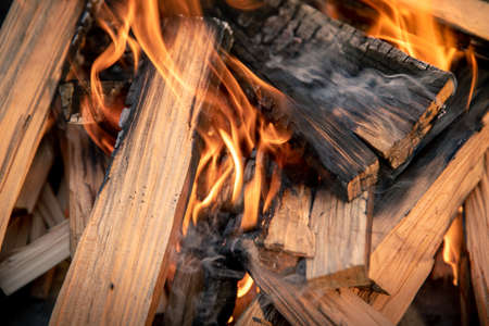 Closeup of pyre of burning wood with flames. Production of charcoal for grilling meat. Wood logs...