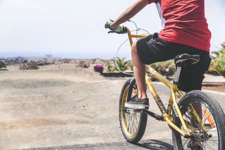 Close up view of a young cyclist with bmx ready to start. Young boy riding a bicycle looking the race track. A child having fun outdoor in the park on a summer day. Competition, youth, sport, concept.の写真素材