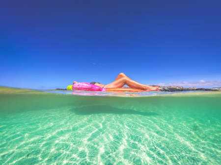 Girl sunbathing on an inflatable mattress floating on blue tropical water. Beautiful woman lying on...