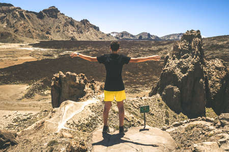 Cute young boy with arms wide open standing in front of the panorama of corona forestal - natural Park of Teide, Tenerife. Summer atmosphere on top of mountain. Freedom and satisfaction goal achieved.の写真素材