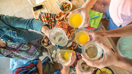 Toast with friend dinner on the terrace enjoying together. Summer aperitif with group of friends. Joy and festivities in family View from the top of a table with many foods and glass in hands cheer upの写真素材