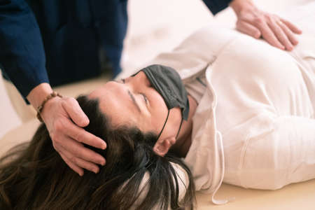 Therapist man doing Holistic therapy Reiki to a woman. Energy treatment with the heat of the palm hands. Japanese energy healing. Wellness, health, relaxation, well-being and alternative medicine concept.の写真素材