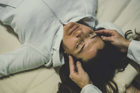 Therapist man doing a Shiatsu massage to a woman. Holistic therapy, treatment with manipulation by thumb, fingers and palms. Wellness, health, relaxation, well-being and alternative medicine concept.の写真素材