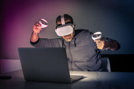 Man playing with virtual reality device. Cyberpunk futuristic mood, immersive experience with video game and VR 3D viewer technology. People using next-generation electronic devices. Tech conceptの写真素材