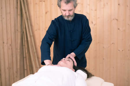 Therapist man doing Holistic therapy Reiki to a woman. Energy treatment with the heat of the palm hands. Japanese energy healing. Wellness, health, relaxation, well-being and alternative medicine concept.の写真素材